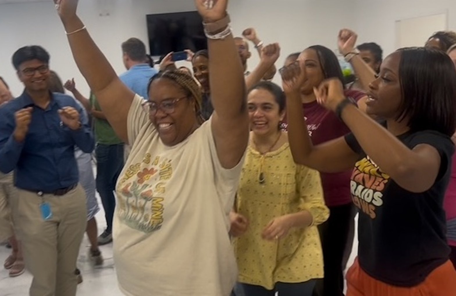 A diverse group of coworkers cheering together during a team celebration